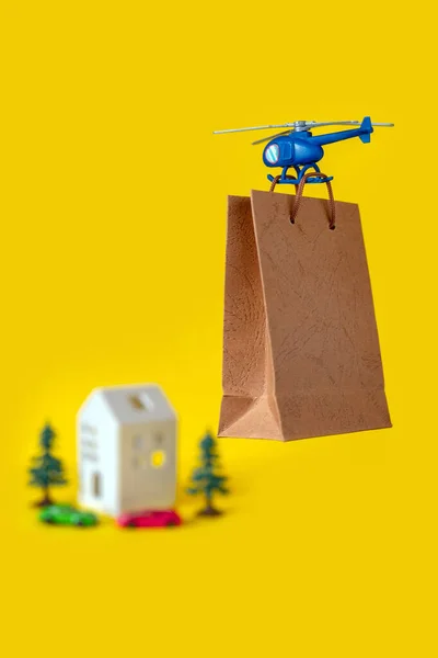 Blue Toy Helicopter Delivers Gift Paper Bag to Toy House. Mother\'s day, Valentine\'s day, Birthday concept.