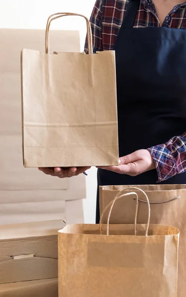 A lot of Craft Paper Bags and Boxes stay near by Packer. Worker of Delivery Service Packing Order for Customer.