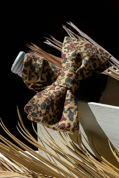 Bottle of red or white wine with Bow Tie on a black background with tropical leaves.