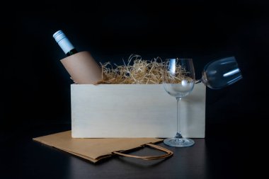 Şarap şişesi ve bardaklar siyah arka planda samanla beyaz kutuda. Müşteri Taşıma Hizmeti Konsepti.