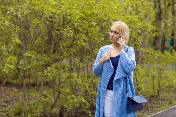 The lonely woman in a beautiful knitted jacket. The beautiful woman on walk. Fashionable clothes.