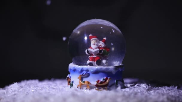 Santa y su ayudante muñeco de nieve, en una bola de cristal, lee una lista de regalos para los niños para las vacaciones de Navidad — Vídeos de Stock