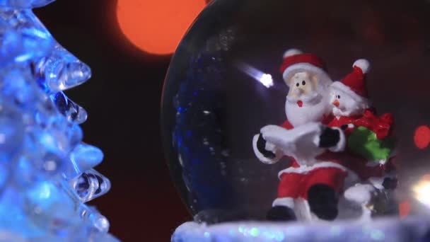 Santa cerca del abeto hermoso, colorido, de Año Nuevo, se sienta en la esfera de cristal y prepara los regalos para los niños para un nuevo año — Vídeo de stock