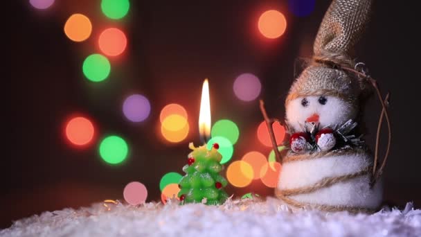 Muñeco de nieve en la nieve cerca de un abeto de Navidad y coloridos y brillantes fuegos — Vídeo de stock