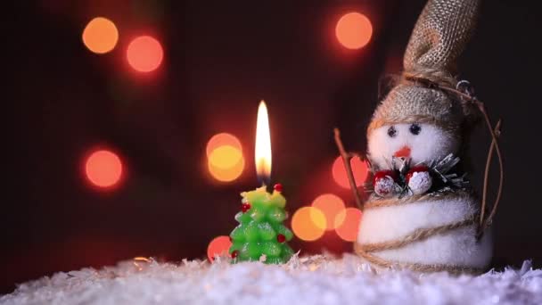 クリスマスのモミの木とカラフルで明るい火の近くの雪の上の雪だるま — ストック動画
