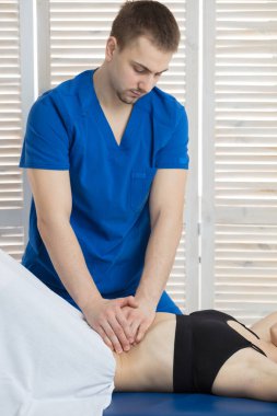 Doktor, hastanın karın boşluğunun kaslarını teşhis ediyor. Mide kaslarının gerilmesinin giderilmesi. Mide kasları bir tonda