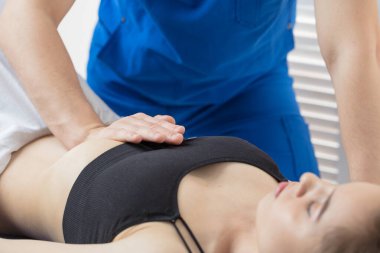 Doktor, hastanın karın boşluğunun kaslarını teşhis ediyor. Mide kaslarının gerilmesinin giderilmesi. Mide kasları bir tonda