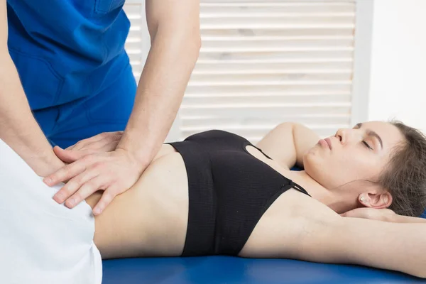 Doktor, hastanın karın boşluğunun kaslarını teşhis ediyor. Mide kaslarının gerilmesinin giderilmesi. Mide kasları bir tonda