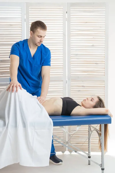 The doctor does diagnostics of muscles of an abdominal cavity of the patient. Removal of tension of muscles of a stomach. Stomach muscles in a tone