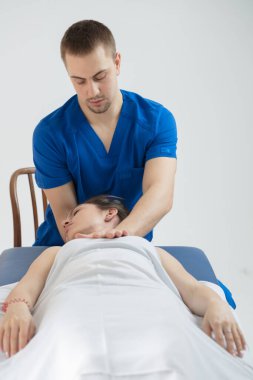 Kadın kanepede yatıyor ve doktor kafanın oksipital kısmına teşhis koyuyor. Manuel terapi..