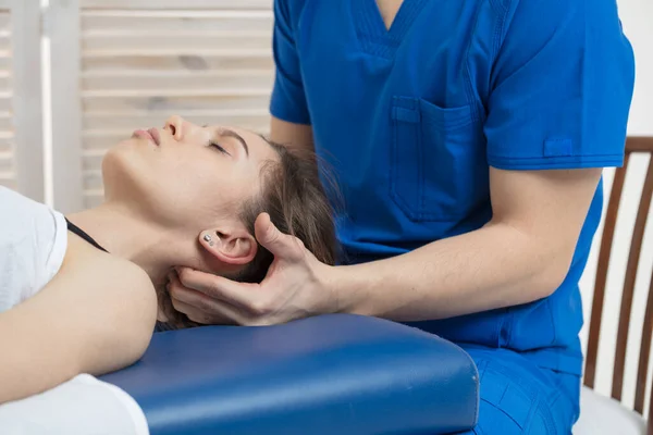 Kadın kanepede yatıyor ve doktor kafanın oksipital kısmına teşhis koyuyor. Manuel terapi..