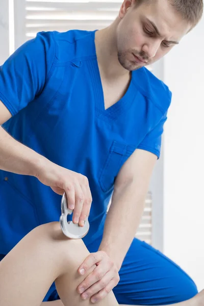 Doktor ortopedist yumuşak dokunun hareketliliğini artırmak için özel masaj aleti ve bıçak yapıyor. Manuel terapi.