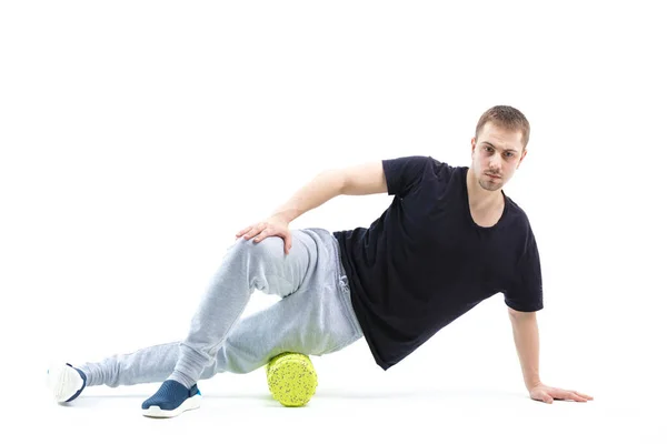 Bir erkek, vücut için özel spor ekipmanlarıyla güçlendirici egzersizler yapar. Kendine masaj vücudun tonunu artırır.