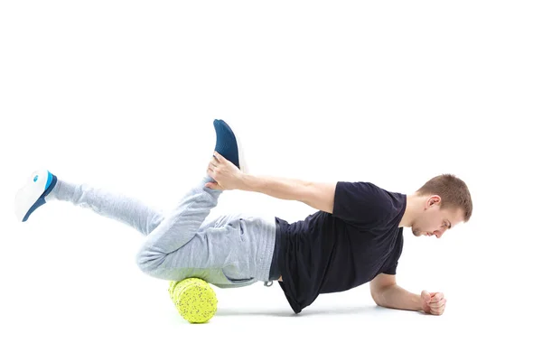 Bir erkek, vücut için özel spor ekipmanlarıyla güçlendirici egzersizler yapar. Kendine masaj vücudun tonunu artırır.