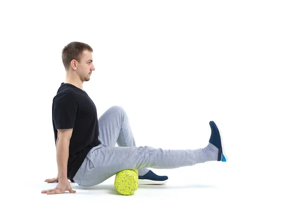 Bir erkek, vücut için özel spor ekipmanlarıyla güçlendirici egzersizler yapar. Kendine masaj vücudun tonunu artırır.