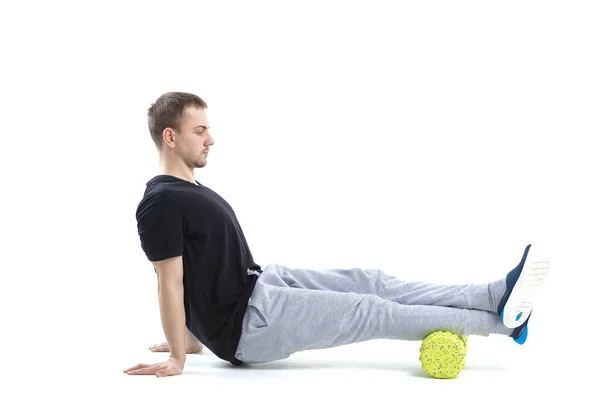 Bir erkek, vücut için özel spor ekipmanlarıyla güçlendirici egzersizler yapar. Kendine masaj vücudun tonunu artırır.