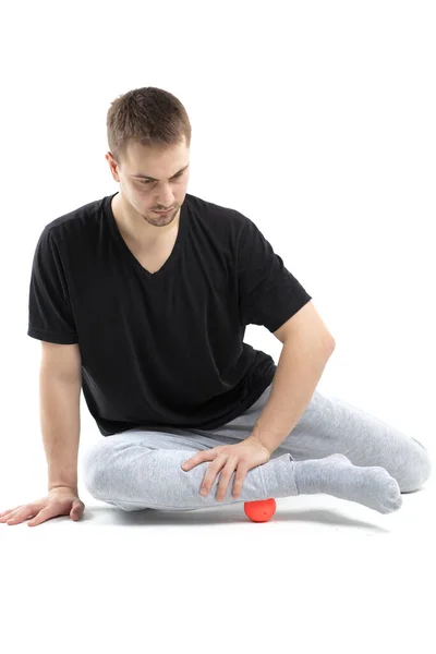 Bir erkek, vücut için özel spor ekipmanlarıyla güçlendirici egzersizler yapar. Kendine masaj vücudun tonunu artırır.