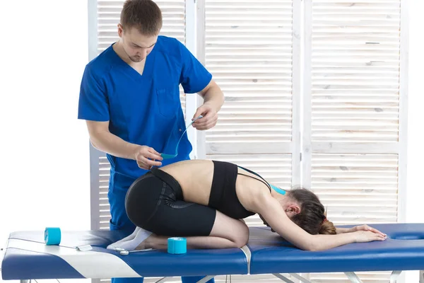 Doktor, genç bir kız için omurgayı bantlama prosedürünü uyguluyor.