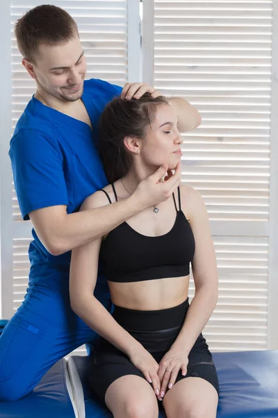 Doktor genç bir kızın kafa ve boyun omurgasına teşhis koyuyor. Masaj ve manuel terapi