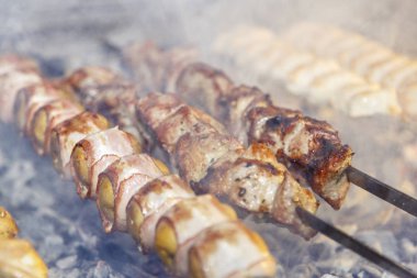 Pastırmaya sarılı patatesler, şişte kızartılmış ve ızgarada kızartılmış. Etle birlikte şişlerin yanında.