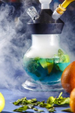 Yeşil likörlü nargile şişesi. Dilimlenmiş greyfurt ve nane yaprakları likör içinde yüzer.. 