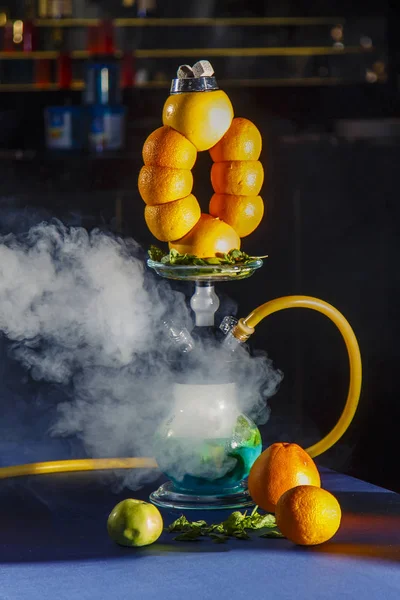 Hookah en la naranja. Naranja hookah. Hookah con un matraz redondo transparente en el que las naranjas en rodajas y las hojas de menta flotan en licor rojo . — Foto de Stock