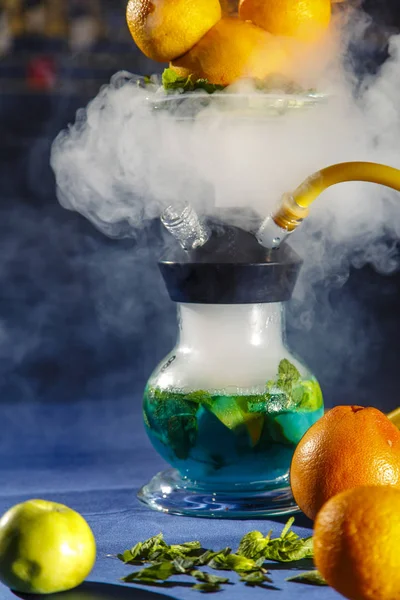 Hookah on the orange. Orange hookah. Hookah with a round transparent flask in which sliced oranges and mint leaves float in red liquor.