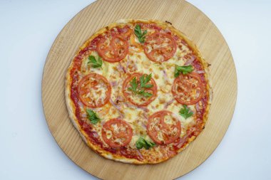 Sosisli, peynirli ve domatesli pizza, halka şeklinde kesilmiş. Hafif ahşap tabakta pizza. 45 derece kenar görünüm