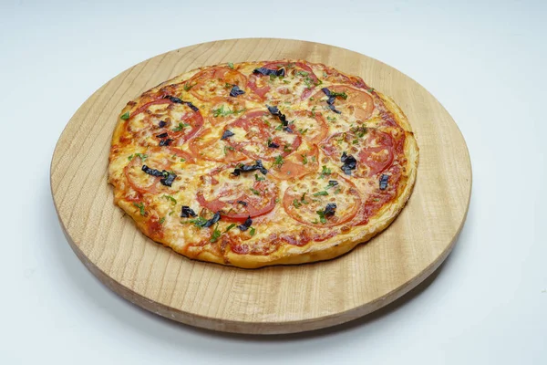 Pizza with slices of sausage, cheese, olives and tomatoes cut into rings. The pizza is cut into pieces, one pushed away from the others.