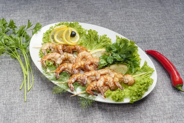 King prawns on a lettuce leaf on a white plate. Decorated with lemon, olives and parsley. — Stock Photo, Image