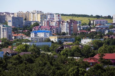 Şehir manzarası. Yokuşta çok katlı çok katlı evler var. Ritim, pencereler, çatılar. Şehirde gayrimenkul