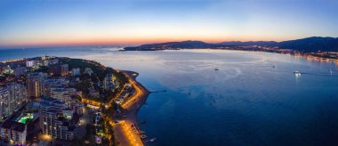 Gelendzhik sahil beldesinin akşam manzarası. Güneş battı, koyu mavi gökyüzü ve deniz. Visible Bay, plaj ve ışıklarda gezinti. Şehir çok güzel aydınlatılmış..