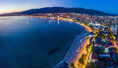 Gelendzhik sahil beldesinin akşam manzarası. Güneş battı, koyu mavi gökyüzü ve deniz. Visible Bay, plaj ve ışıklarda gezinti. Şehir çok güzel aydınlatılmış.. 
