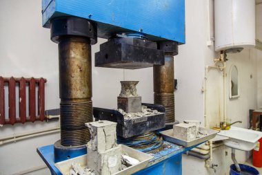 İnşaat laboratuarı. Basın kübik beton örneğini parçalara ayırıyor ve betonun gücünü inceliyor.. 