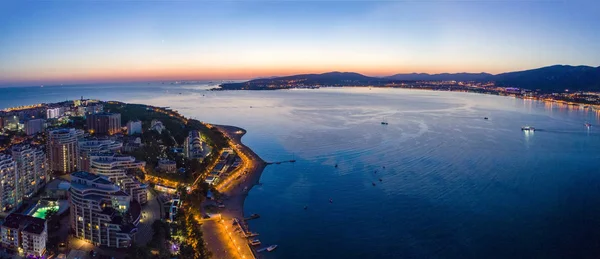 Gelendzhik sahil beldesinin akşam manzarası. Güneş battı, koyu mavi gökyüzü ve deniz. Visible Bay, plaj ve ışıklarda gezinti. Şehir çok güzel aydınlatılmış.. — Stok fotoğraf