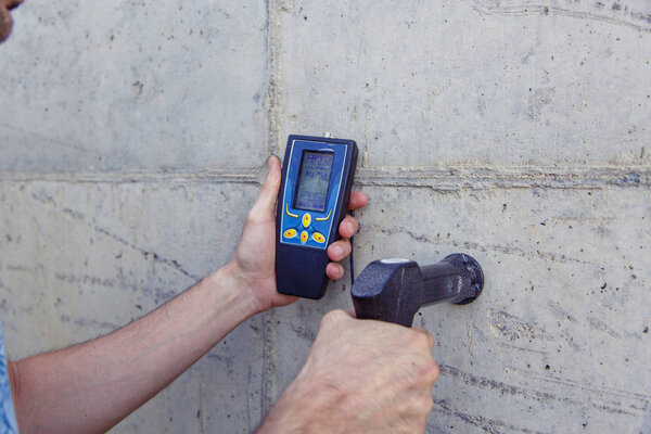 A person examines the concrete and determines the properties, density and quality of the finished concrete with a special device. 