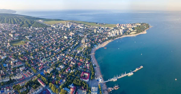 Gelendzhik atirando de um drone. Um promontório íngreme e espesso com um farol e a parte central da cidade com um cais de mar . — Fotografia de Stock