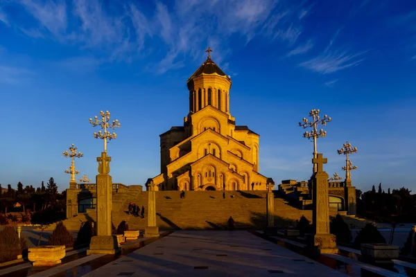 Tiflis. Foto de invierno La Catedral de la Santísima Trinidad (tsminda Sameba) es la iglesia principal de Georgia. Naranja brillante puesta de sol ilumina la Catedral — Foto de Stock