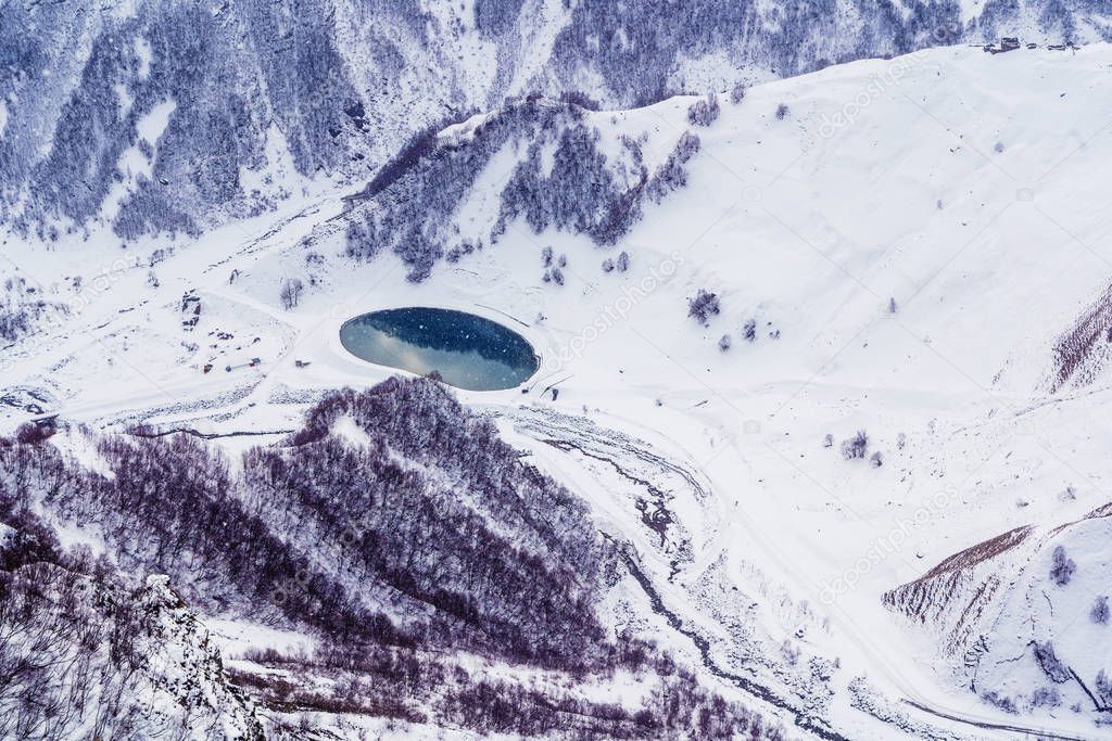 Snow-capped mountain peaks and deep gorges in the area of cross pass, Georgia.  Round lake in the gorge