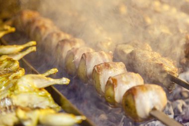 Pastırmaya sarılı patatesler, şişte kızartılmış ve ızgarada kızartılmış. Etle birlikte şişlerin yanında.