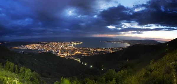 Gelendzhik Bay vanuit vogelperspectief. foto bij zonsondergang. Kaukasus bergen op de voorgrond. verlichte straten van de stad. donkerblauwe lucht, mooie donkere wolken — Stockfoto