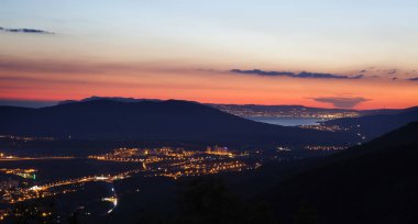 Kafkasya dağlarından Novorossiysk Körfezi 'nin panoraması. Parlak ışıklar, suda yansıma. Araba ışıkları, dağlar. yollar. 