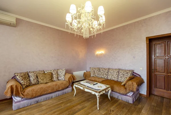 Dos sofás y una mesa blanca con patas curvas en la cabaña. Los sofás están cubiertos con una colcha de color beige — Foto de Stock