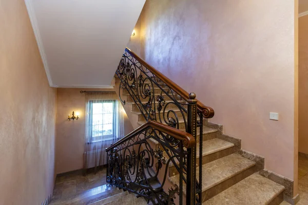 一个富丽堂皇的楼梯，有锻铁栏杆和木制扶手，通往有两扇木门和衣柜的楼梯平台 — 图库照片