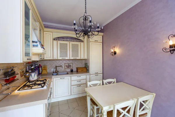 Роскошная современная бежевая кухня в стиле Прованс, розовая стена, кованая черная люстра — стоковое фото