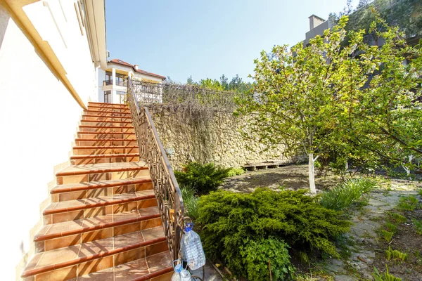 El patio trasero de una casa de campo clásica en la primavera. Delante de la cabaña hay un gran césped verde con césped recortado, árboles con flores, caminos y senderos. Diseño del paisaje — Foto de Stock