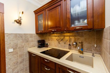 Kulübede küçük bir mutfak. Lavabo ve elektrikli soba. Rafın üstünde ve tabaklar var..