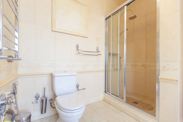 Элегантная и богатая ванная комната в классическом стиле в бежевых тонах. Душ, туалет, красивая бежевая керамическая плитка с растительным рисунком на одном ряду . — стоковое фото