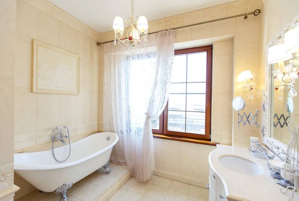 Элегантная и богатая ванная комната в классическом стиле в бежевых тонах. Элегантная ванная комната, умывальник с зеркалом, окно, красивая бежевая керамическая плитка с цветочным узором на одном ряду . — стоковое фото