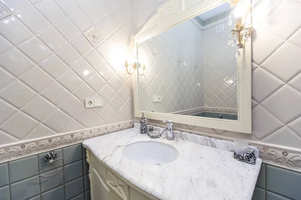 Просторная роскошная винтажная ванная комната. Стены облицованы дорогими и красивыми плитками синего и белого цветов. Раковина в мраморной столешнице с винтажным краном — стоковое фото